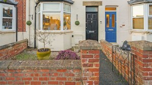 A two-story terraced house with a front door, bay windows, and a small garden area with a potted plant. - Cotswolds 3BD 1 5 Bath Garden City Centre (Cirencester)