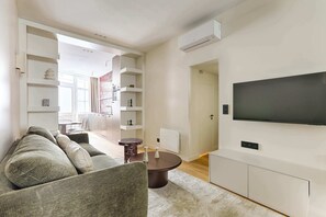 Moderni olohuone, jossa on sohva, sohvapöytä ja seinälle asennettu taulutelevisio.