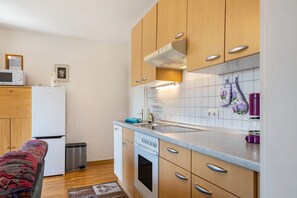 A compact kitchen with wooden cabinets, a built-in microwave, a stove, and a sink.