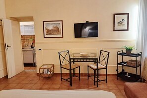 A room with a bed, a dining table with chairs, a TV, and a framed picture on the wall. - Among the historic alleys of Rome (Domus Viola) (Roma)