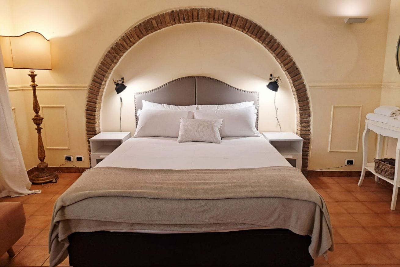 Ein Schlafzimmer mit einem großen Bett, einem Bettrahmen mit Bogenform, Nachttischlampen, einem Nachttisch und einer Stehlampe.