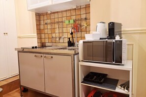 A kitchen with a microwave, coffee maker, and utensils on the wall. - Among the historic alleys of Rome (Domus Viola) (Roma)