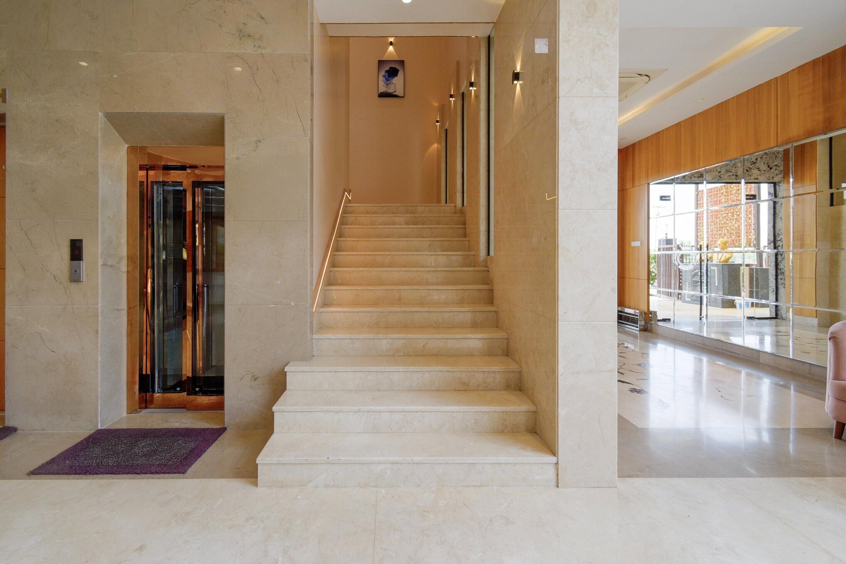 A marble staircase in a hotel lobby with a glass elevator and a view of the outside.