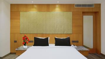 Une chambre d’hôtel avec un grand lit, une tête de lit en bois, des tables de chevet et un panneau de commande fixé au mur.