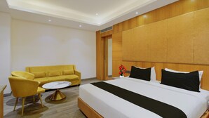 A hotel room with a bed, a sofa, a coffee table, and a wooden headboard. - Palette Rc Platinum Hotel (Mahabubabad)