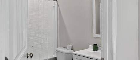 Ein Badezimmer mit Toilette, Duschvorhang, Waschbecken und Spiegel.