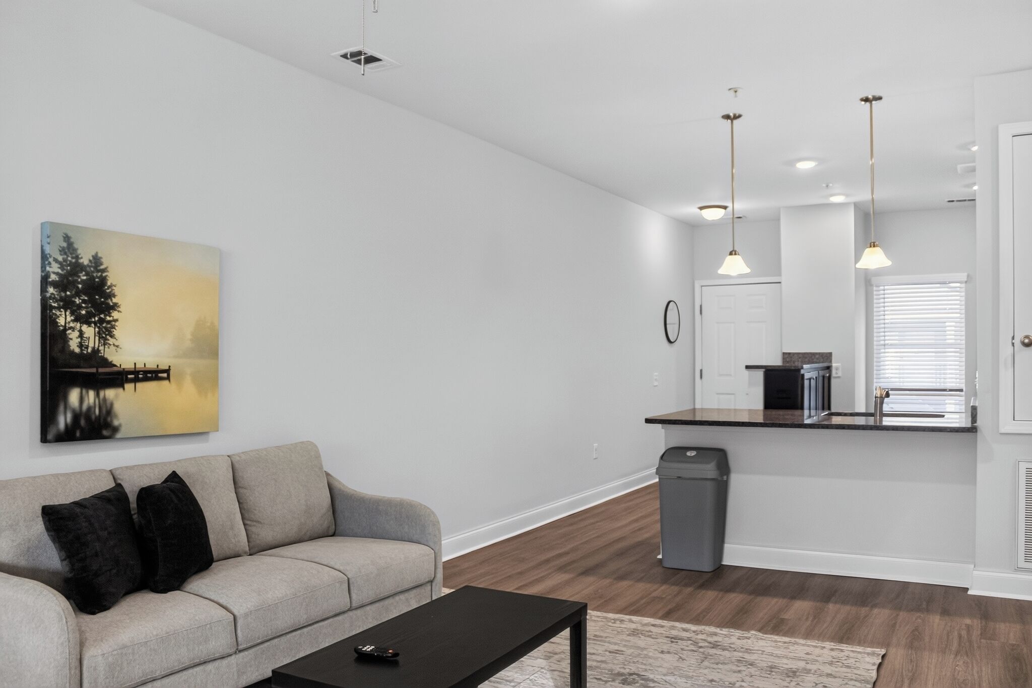 Un salon moderne avec un canapé, une table basse et un tableau accroché au mur.