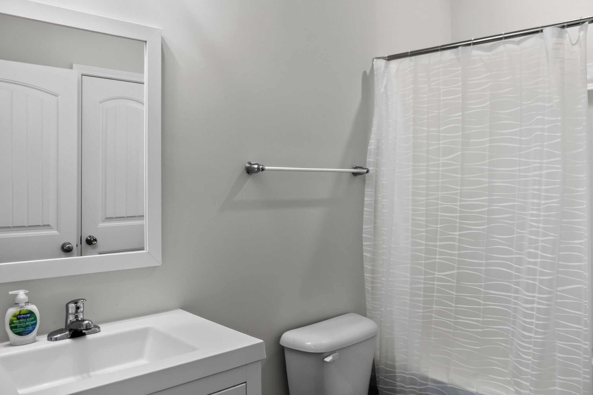 A bathroom with a white sink, a toilet, a shower curtain, and a towel rack.