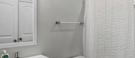A bathroom with a white sink, a toilet, a shower curtain, and a towel rack.