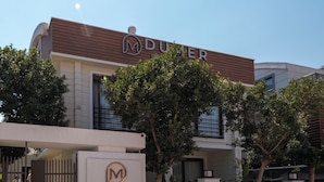 A hotel named 'Dumer Boutique Hotel' with a modern architectural design, featuring a prominent sign and a gated entrance.
