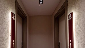 A hallway with a red carpet, two doors with illuminated signs, and a ceiling light.