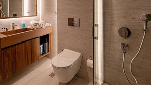 A modern bathroom with a wooden vanity, a toilet, a glass shower enclosure, and a large mirror.