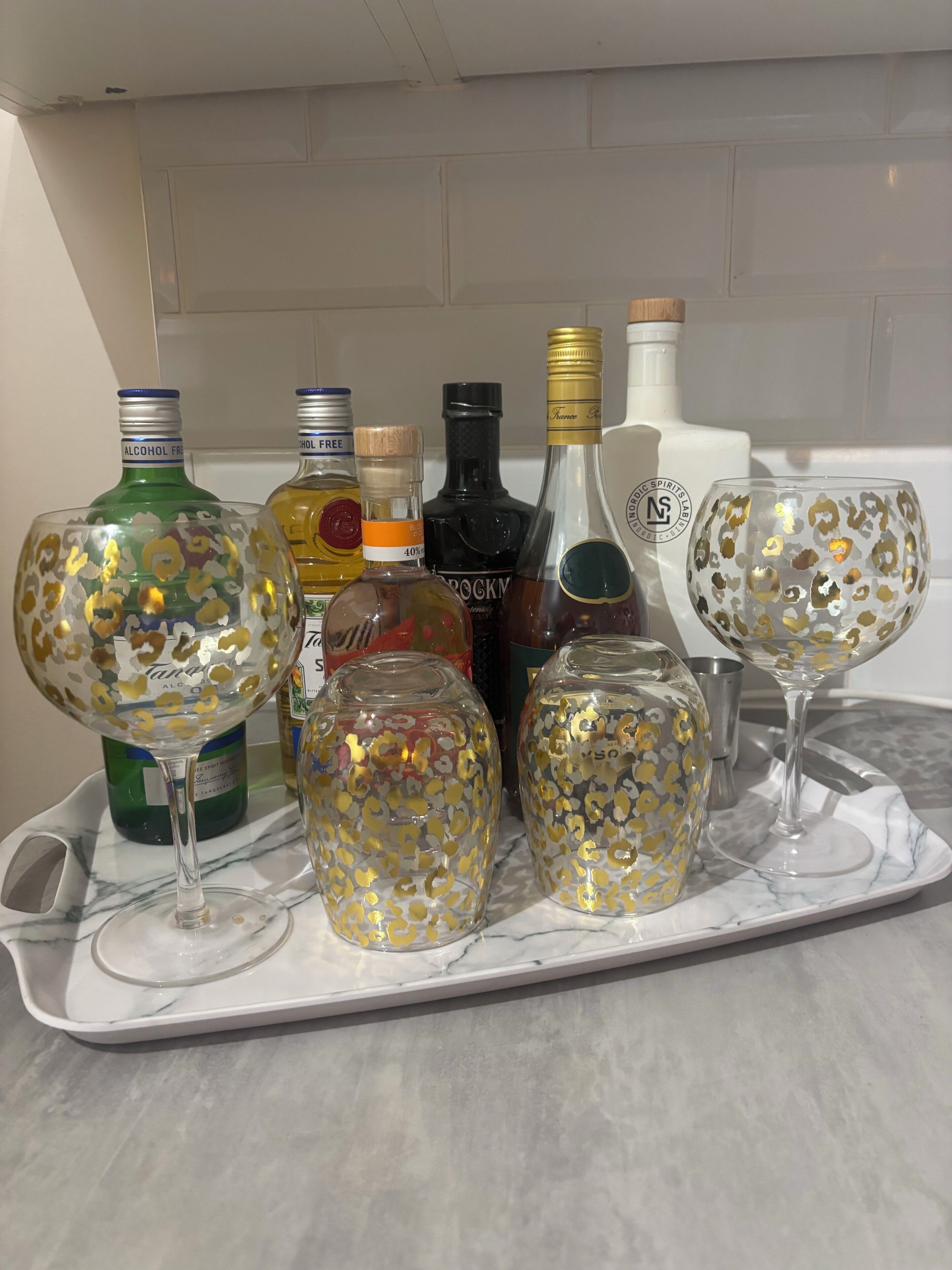 Un plateau contenant divers verres et bouteilles, posé sur un comptoir en marbre.