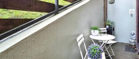 A patio with a white table and chairs, a potted plant, and a statue.