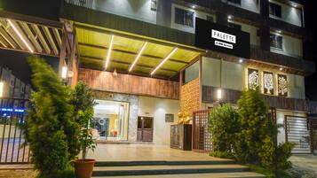 Entrada de hotel con un vestíbulo cubierto, mostrador de recepción y un cartel que indica el nombre 'PALETTE'.