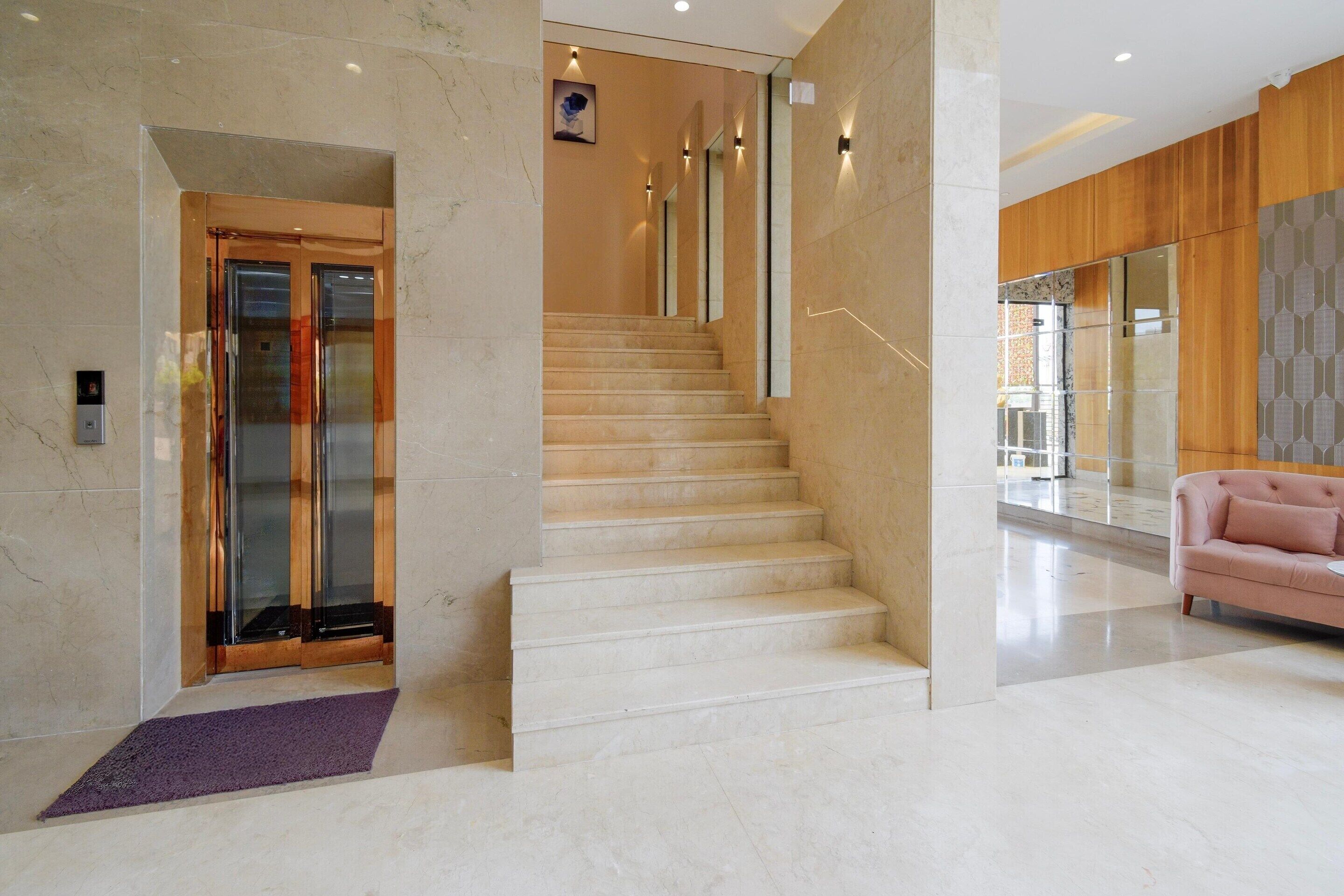 Un intérieur moderne avec un escalier en marbre, un espace d’accueil et un canapé rose.
