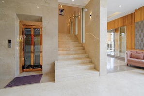 Un interior moderno con una escalera de mármol, una zona de recepción y un sofá rosa.