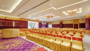 Un salón de conferencias con filas de sillas, una alfombra estampada y una araña.