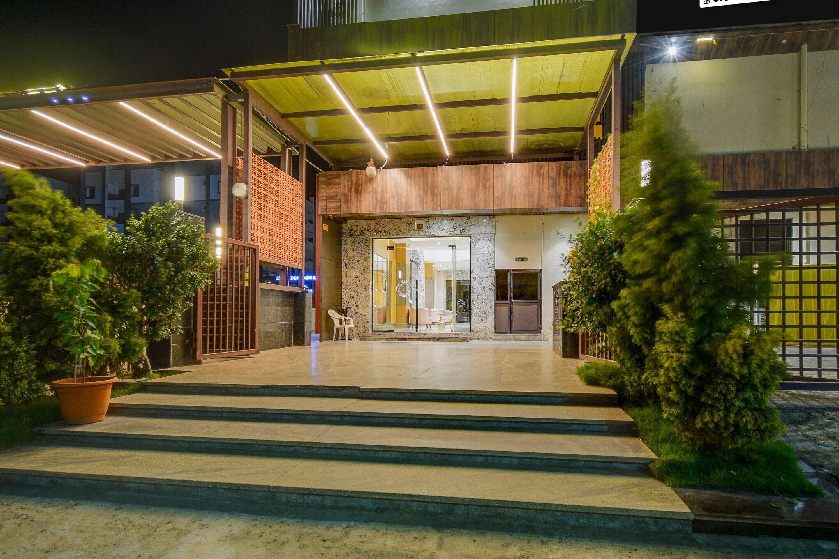 A hotel entrance with a covered walkway, steps leading to the entrance, and potted plants on either side.