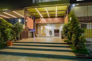 A hotel entrance with a covered walkway, steps leading to the entrance, and potted plants on either side. - Palette Rc Platinum Hotel (Mahabubabad)