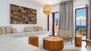 Una sala de estar moderna con un amplio sofá modular, una mesa de centro redonda de madera, un sillón de mimbre y una gran obra de arte en la pared.