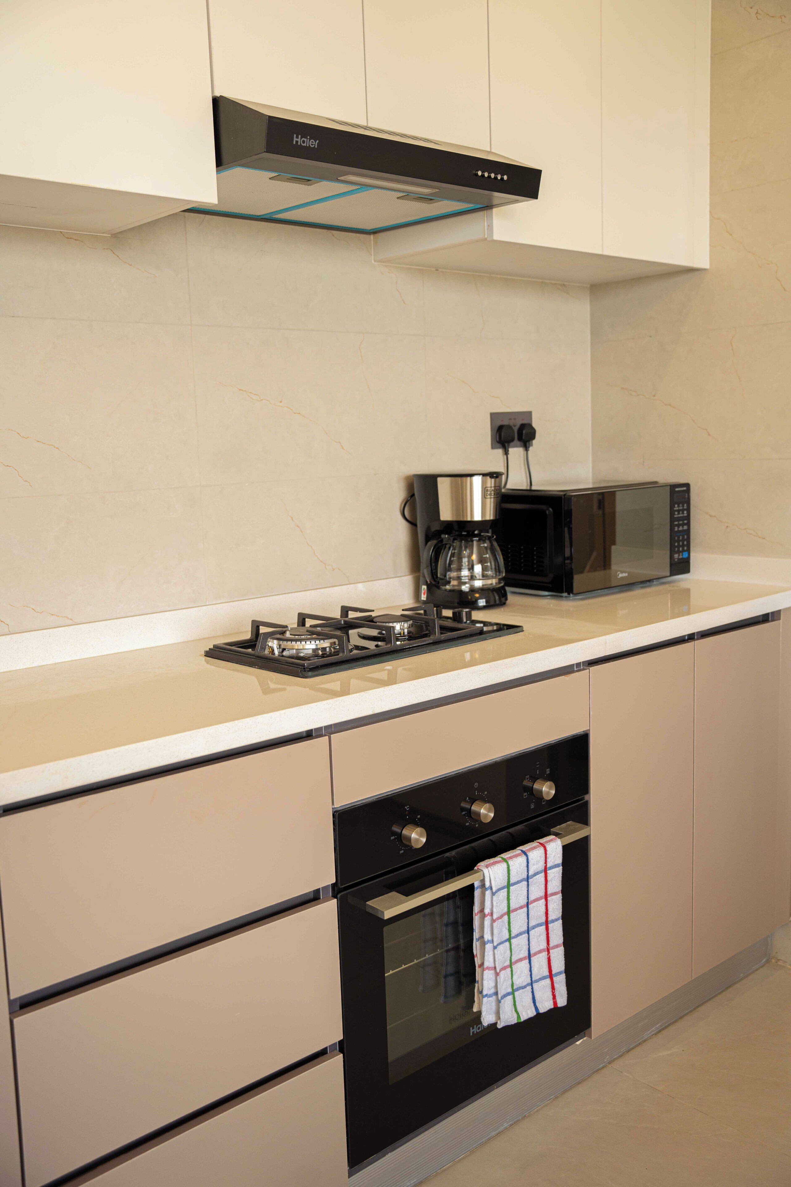Een keuken met een gasfornuis, een koffiezetapparaat, een magnetron en een oven.