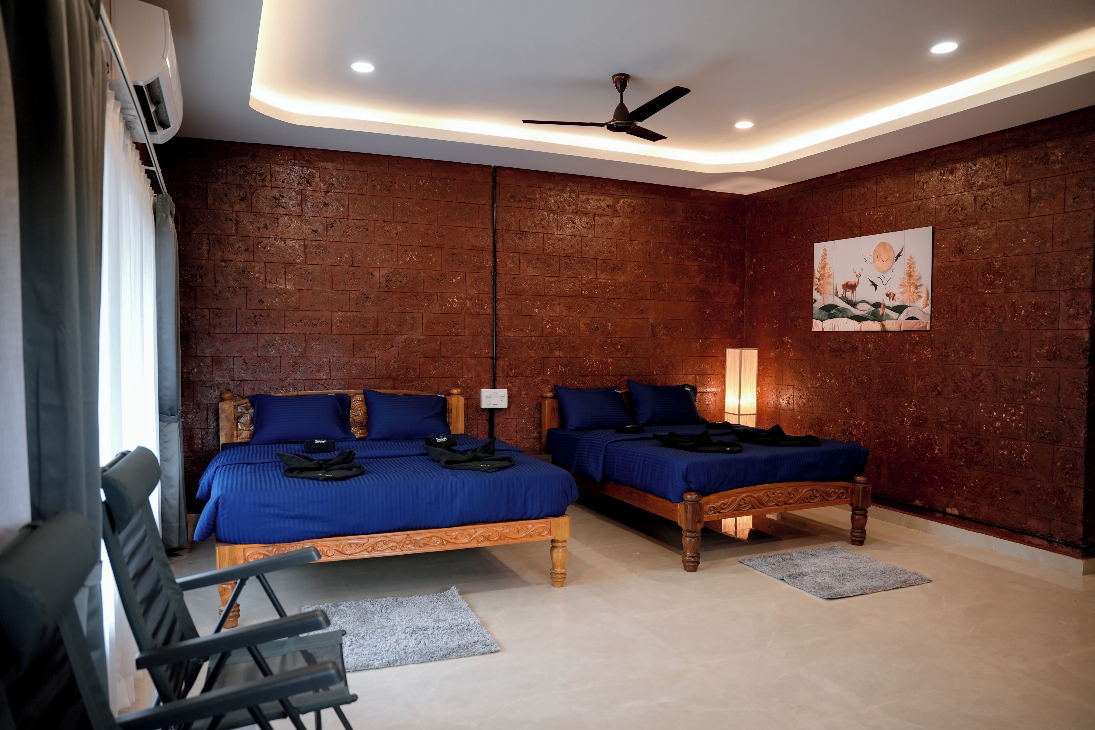 A room with two beds, a ceiling fan, and a brick wall.