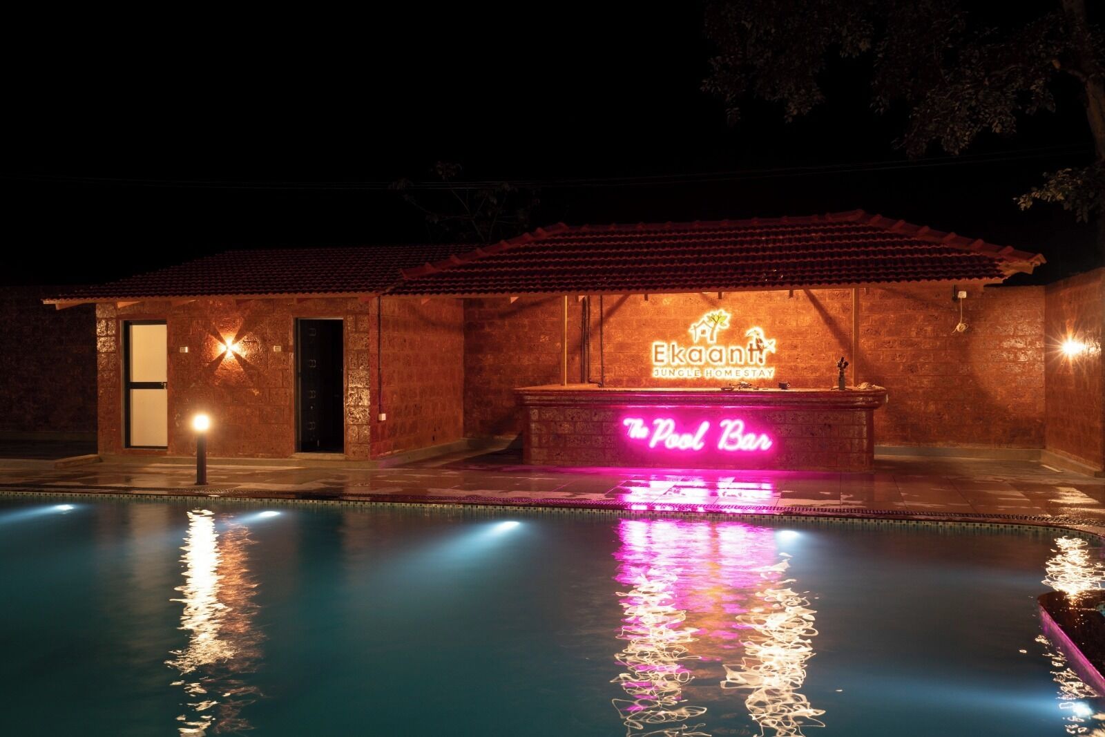 Un edificio con piscina, un letrero de neón que dice 'The Pool Bar' y fachada de ladrillo.