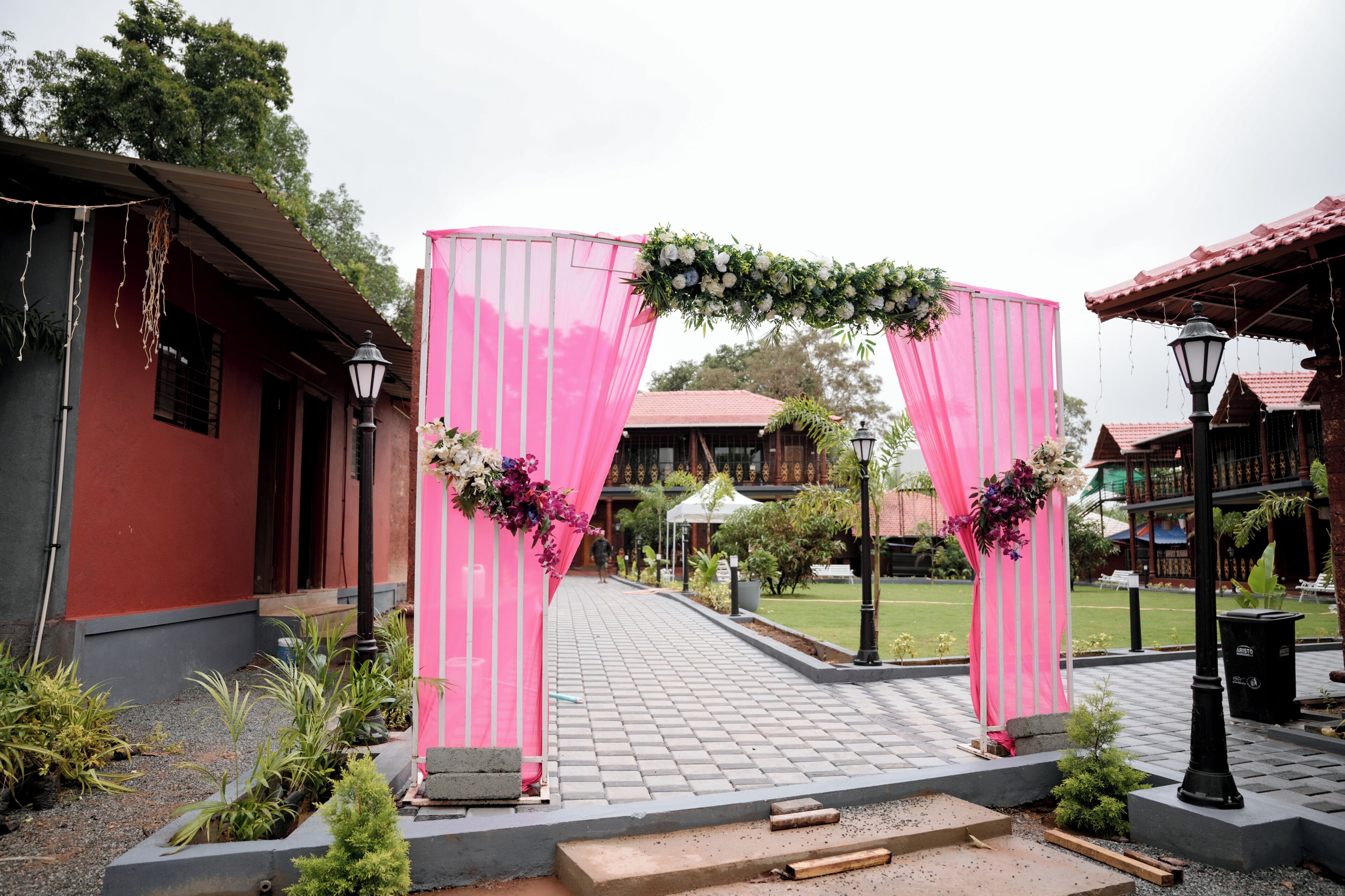 Un chemin menant à un bâtiment dont les fenêtres sont ornées de rideaux roses et de décorations florales.