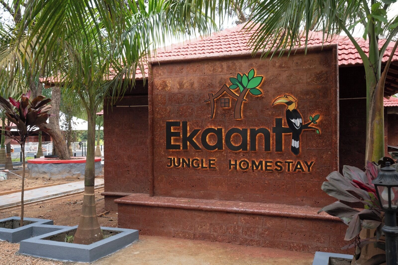 A sign for 'Ekaant Jungle Homestay' with a logo featuring a tree and a bird.