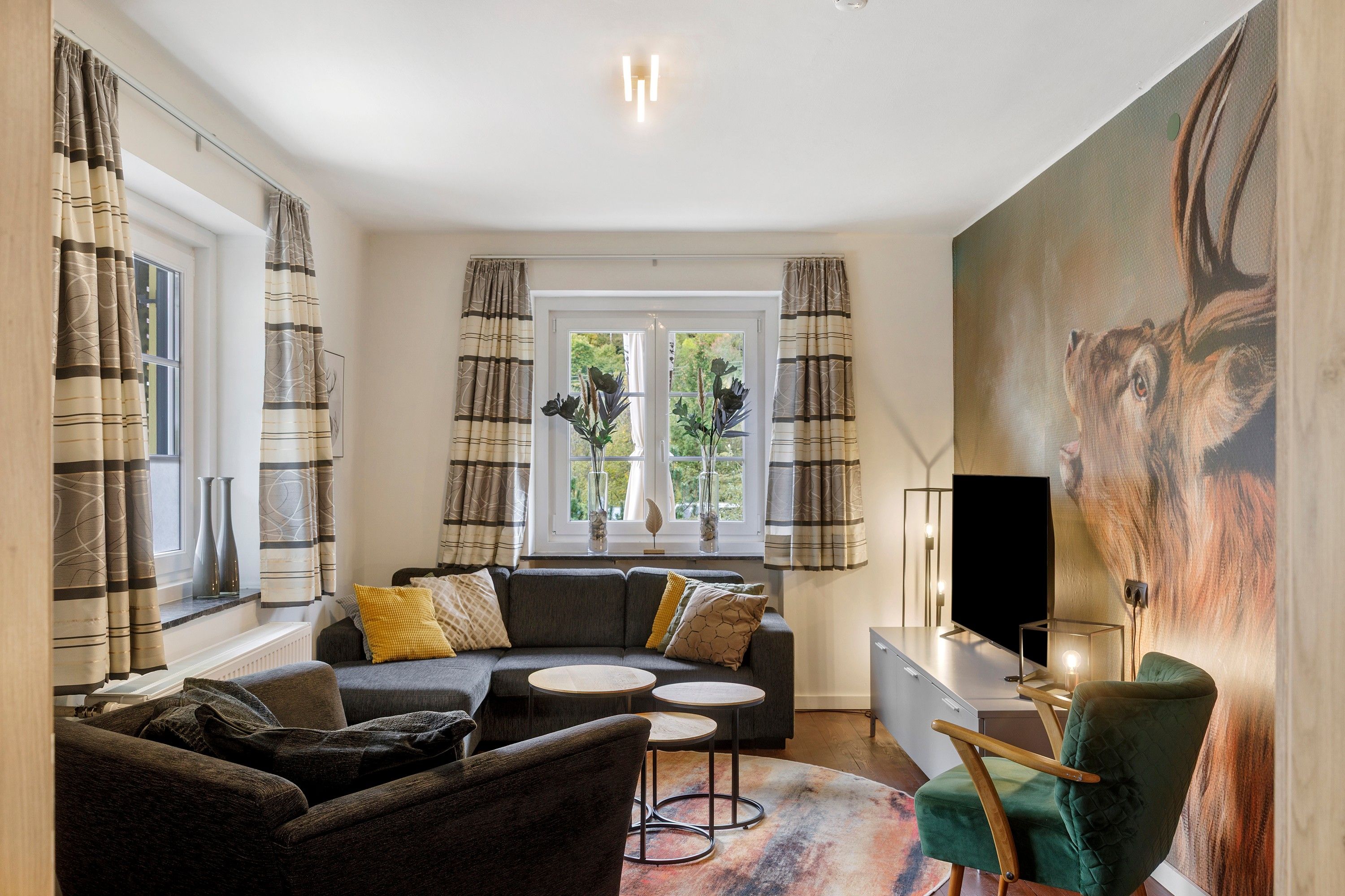 Ein modernes Wohnzimmer mit einer Couch, Sesseln, einem Couchtisch und einem Fernseher.
