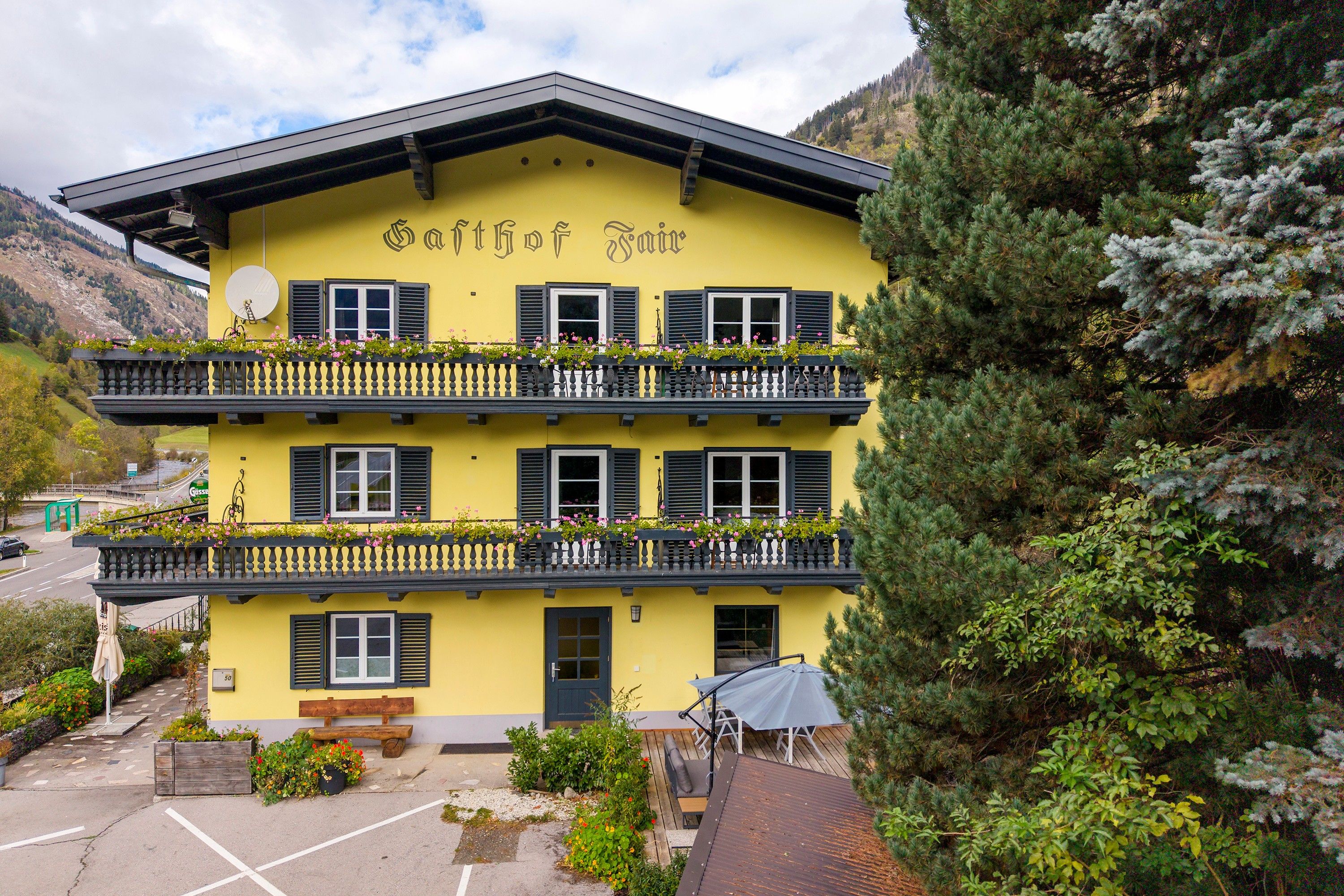 Un edificio a due piani con balconi, un cartello con su scritto 'Gothof Inn' e un'area di parcheggio antistante.