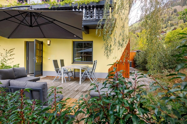 A patio with a table and chairs, a sofa, and a large umbrella.