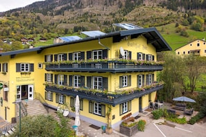 A yellow building with multiple balconies, a staircase, outdoor seating, and solar panels.