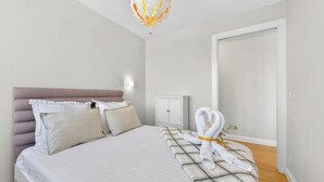 Ein Schlafzimmer mit Bett, Kissen, Nachttisch, Kleiderschrank und Handtüchern.