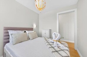 A bedroom with a bed, pillows, a bedside table, a wardrobe, and a towel arrangement. - Elegant 2BR Sea View Apartment Near Monaco | Balcony & Riviera Charm (Roquebrune-Cap-Martin)