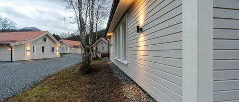 A row of single-story houses with a gravel driveway and a tree in the foreground.