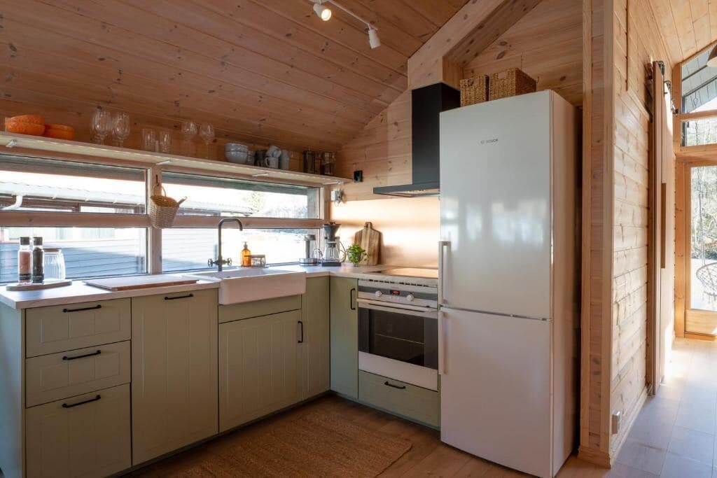 Eine Küche mit Holzschränken, einem Kühlschrank, einem Spülbecken und einem Fenster.