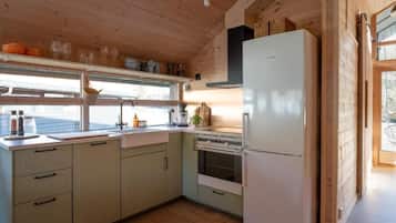 Eine Küche mit Holzschränken, einem Kühlschrank, einem Spülbecken und einem Fenster.