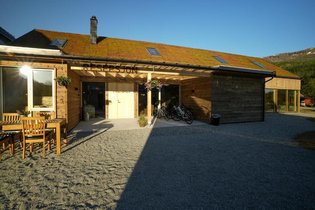 Ein Holzhaus mit geneigtem Dach, einer überdachten Eingangspartei und einer Schotterauffahrt.