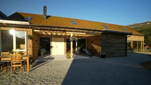 A wooden building with a sloped roof, a covered entrance, and a gravel driveway. - Jølstraholmen Landskapshotell (Sunnfjord)