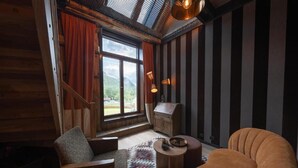 A room with a wooden interior, a window with curtains, a small table, and a sofa. - Jølstraholmen Landskapshotell (Sunnfjord)