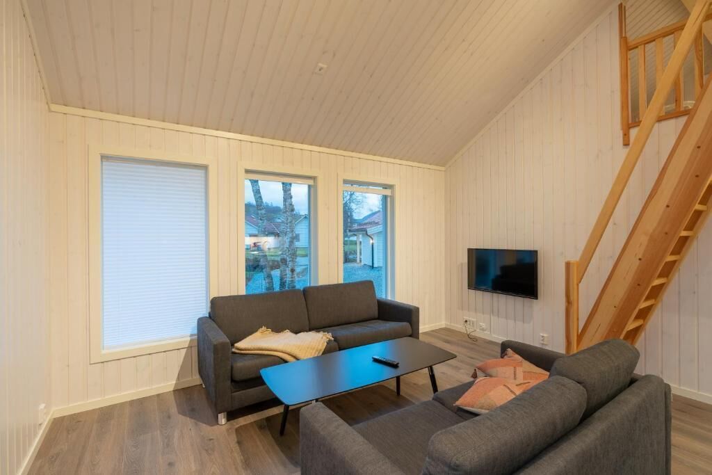 A living room with a sofa, a coffee table, and a TV mounted on the wall.