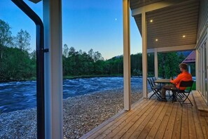 Una terraza de madera con una mesa y sillas con vista al río.
