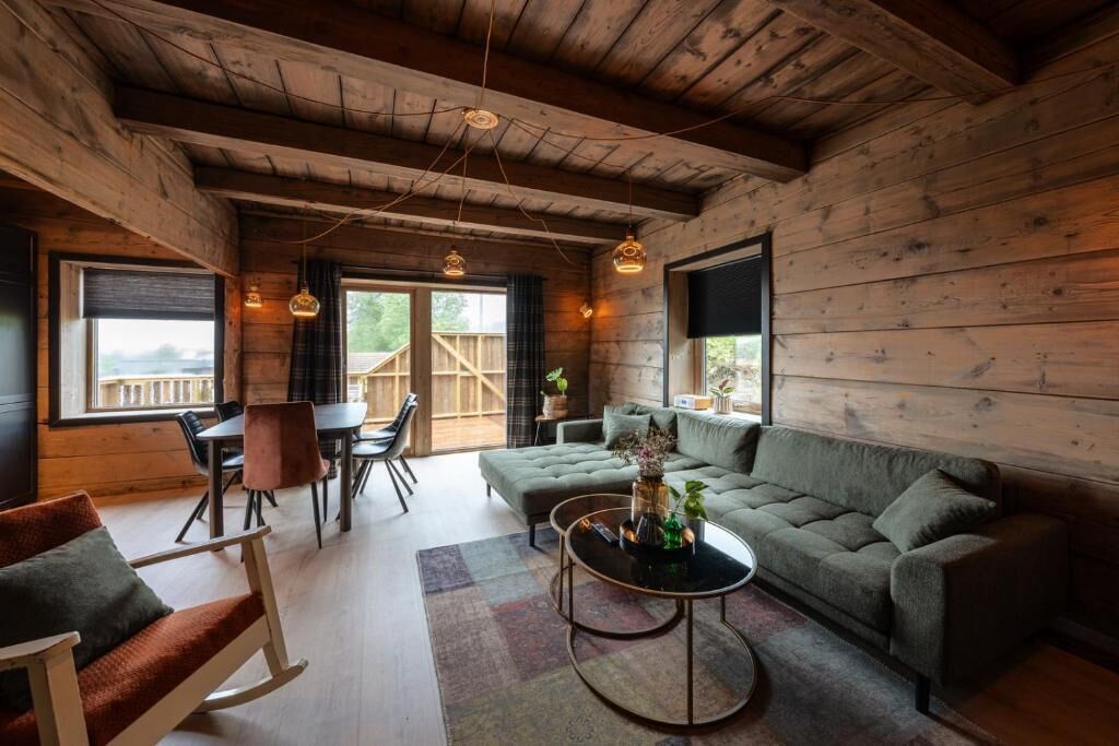 A cozy cabin interior with a sofa, dining table, chairs, and hanging pendant lights.