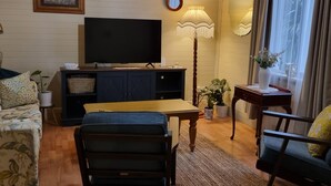 Una sala de estar con televisión, lámpara, mesa de comedor y sofá.