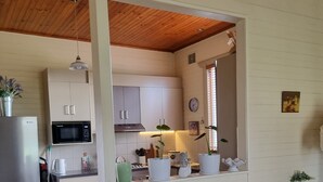 Una sala de estar acogedora con sofá, comedor y cocina equipada con armarios y microondas.
