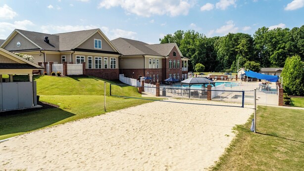 Ett bostadsområde med en swimmingpool, en tennisbana och ett stort hus med ett garage.