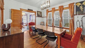 A dining area with a wooden table, black chairs, a red sofa, and a chandelier. - Illini Dream House with Historic Retreat near UIUC and Downtown (Champaign)