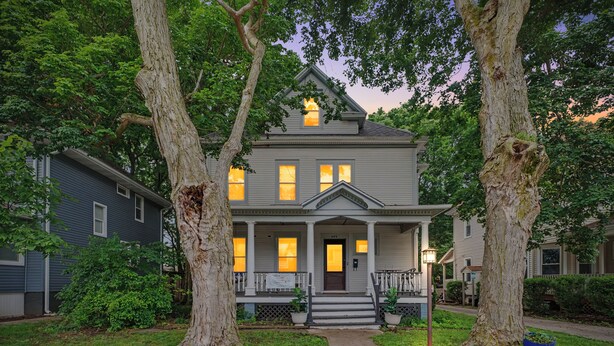 A two-story house with a front porch, a central entrance, and a small front yard. - Illini Dream House with Historic Retreat near UIUC and Downtown (Champaign)